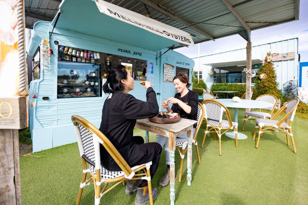 Two women eating oysters at restaurant.