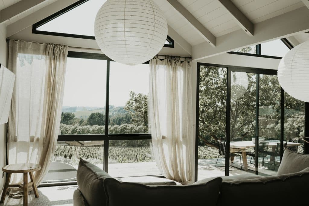 A view looking out a large window onto green gardens and winery.