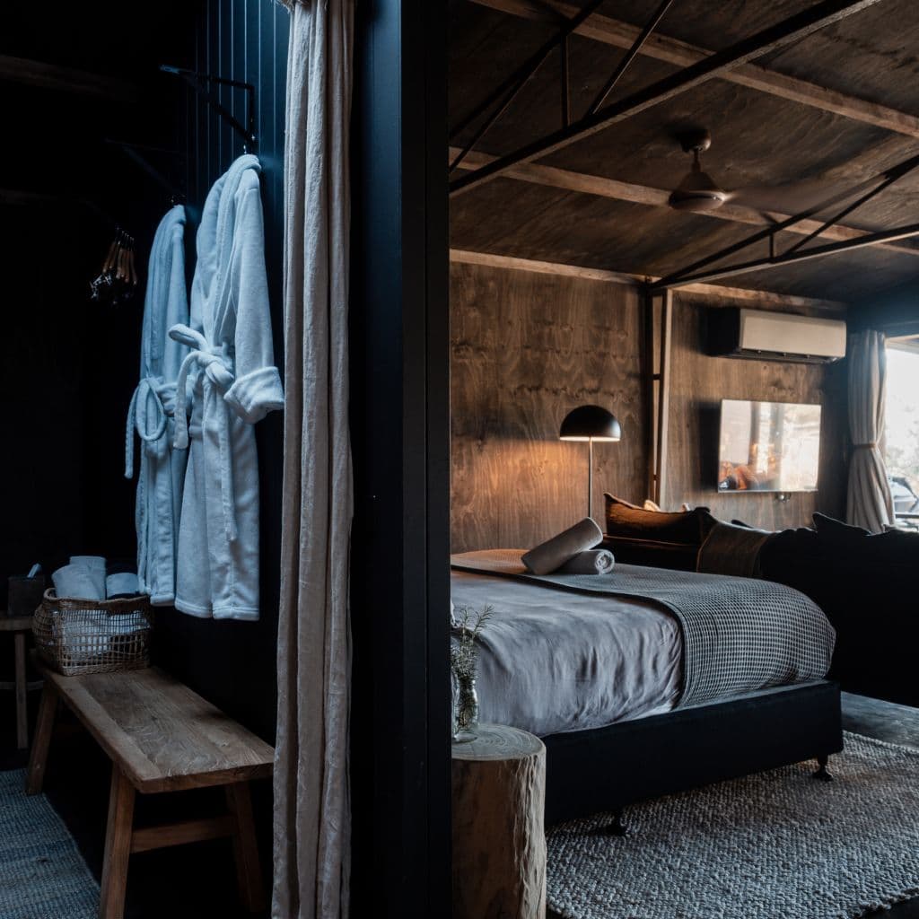 A cosy looking minimalist bedroom with robes hung on the wall.