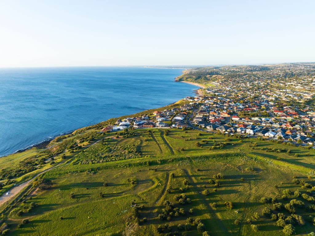 An aerial view showing vast green space and deep blue ocean meeting.