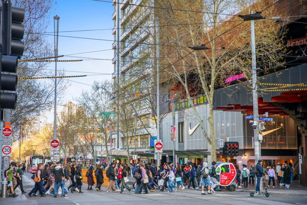 Pedestrians make their way across a street in front of the Nike Store.
