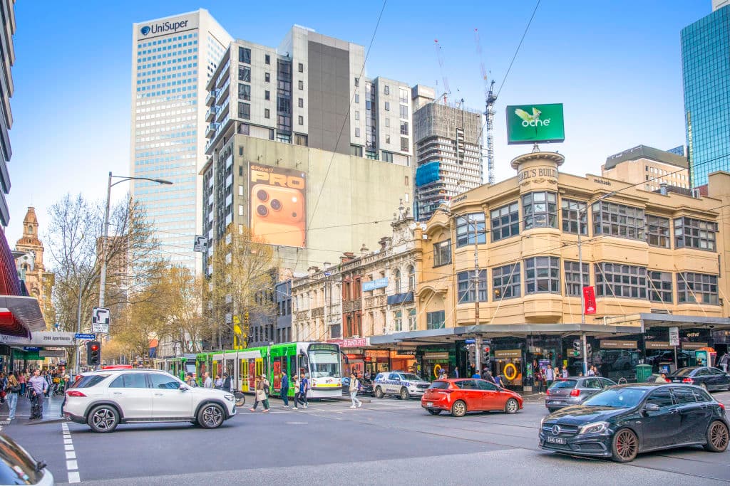 A building corner on Elizabeth Street with cars and trams.