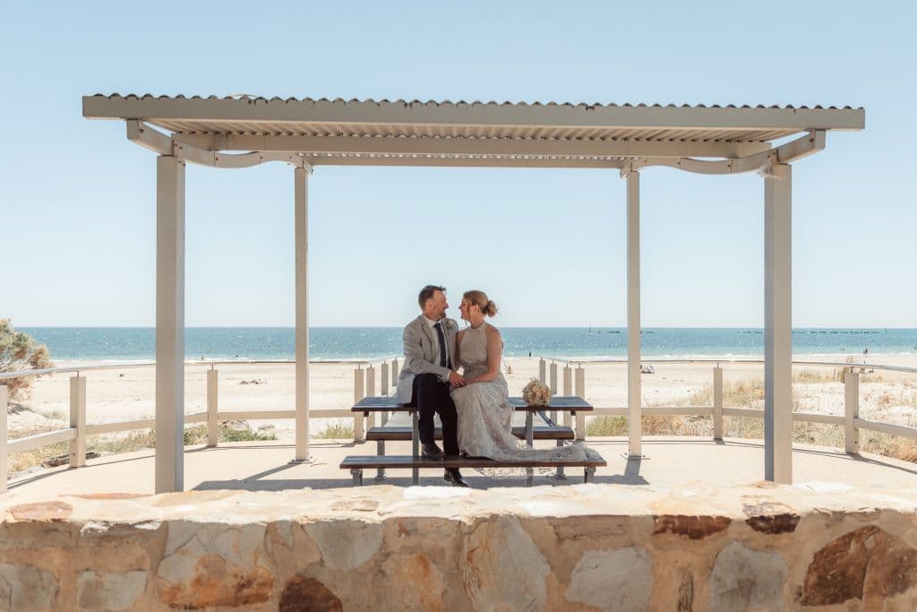 A couple take a moment after getting married on Adelaide's Glenelg Beach through Just Married Weddings, which specialises in elopements and micro-weddings.