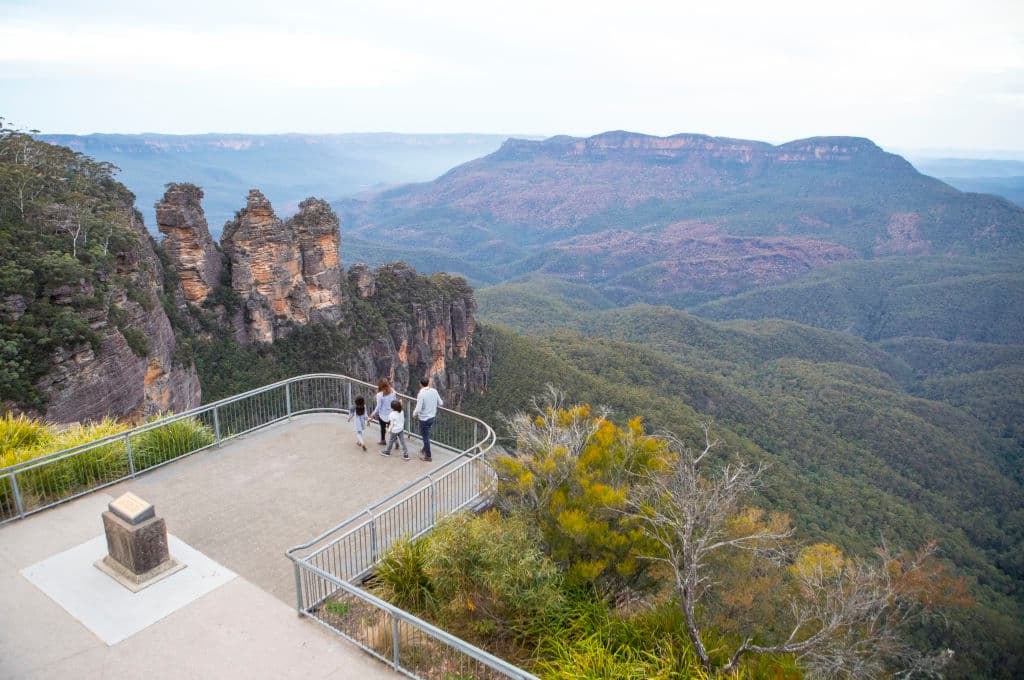 Family enjoying views across Blue Mountains National Park to the Three Sisters and Mount Solitary from Echo Point Lookout. Photo: Destination NSW