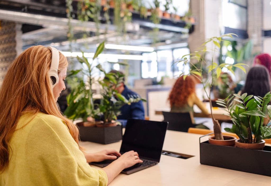 Young woman with headphones working at desk in coworking space