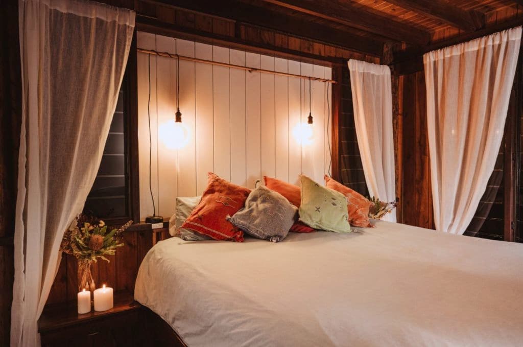 A large bed with cushions and pleasant lighting.