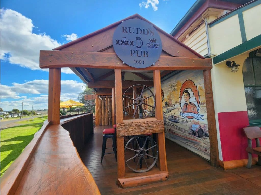 A plaque reading Rudd's Pub at an al fresco area of decking with a mural painted on the pub wall.
