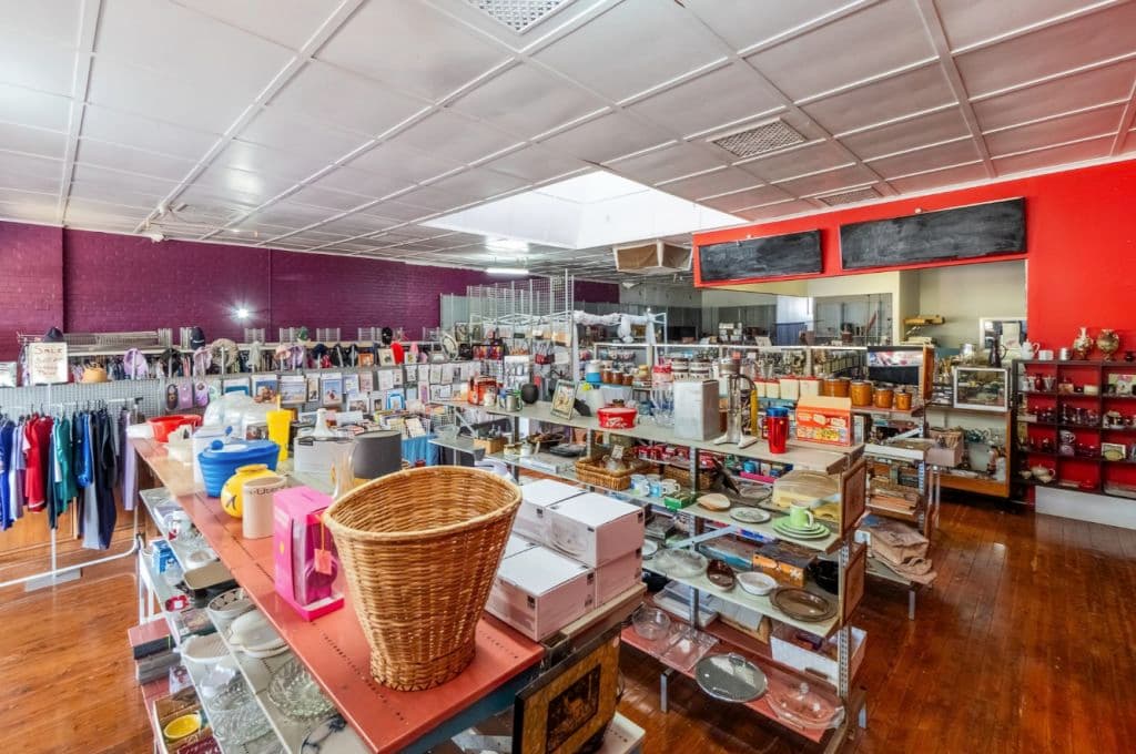 An op-shop interior with racks of goods and high ceilings.