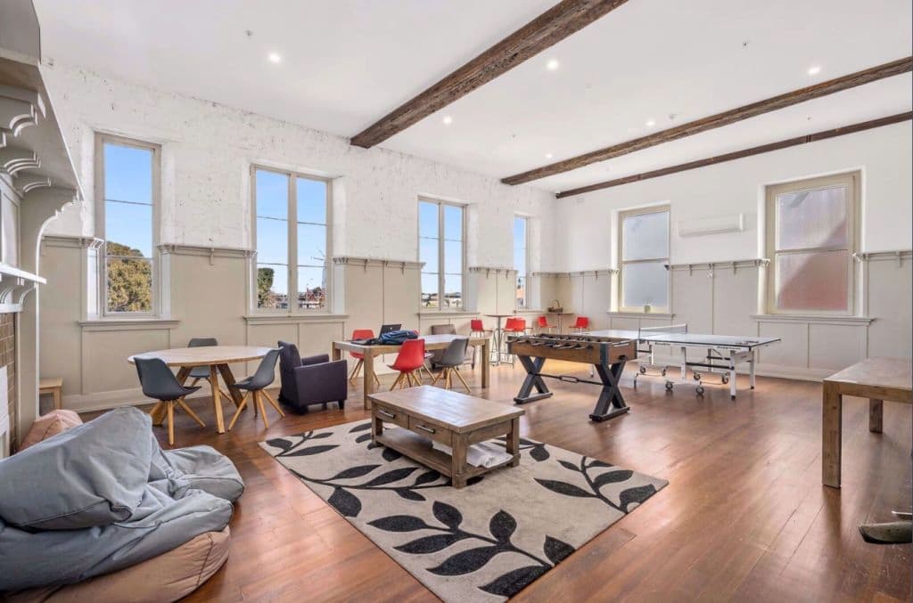 Inside a common room with timber floors and high ceilings and recreational activities.