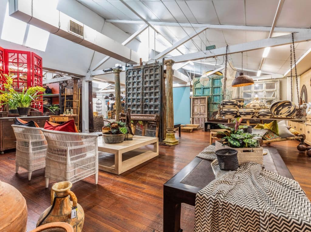 Furniture inside the warehouse building sits on timber floors, with a high roofline.
