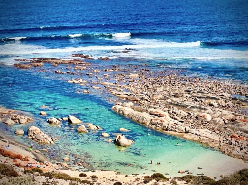 Turquoise waters lap at the water's edge as waves roll in.