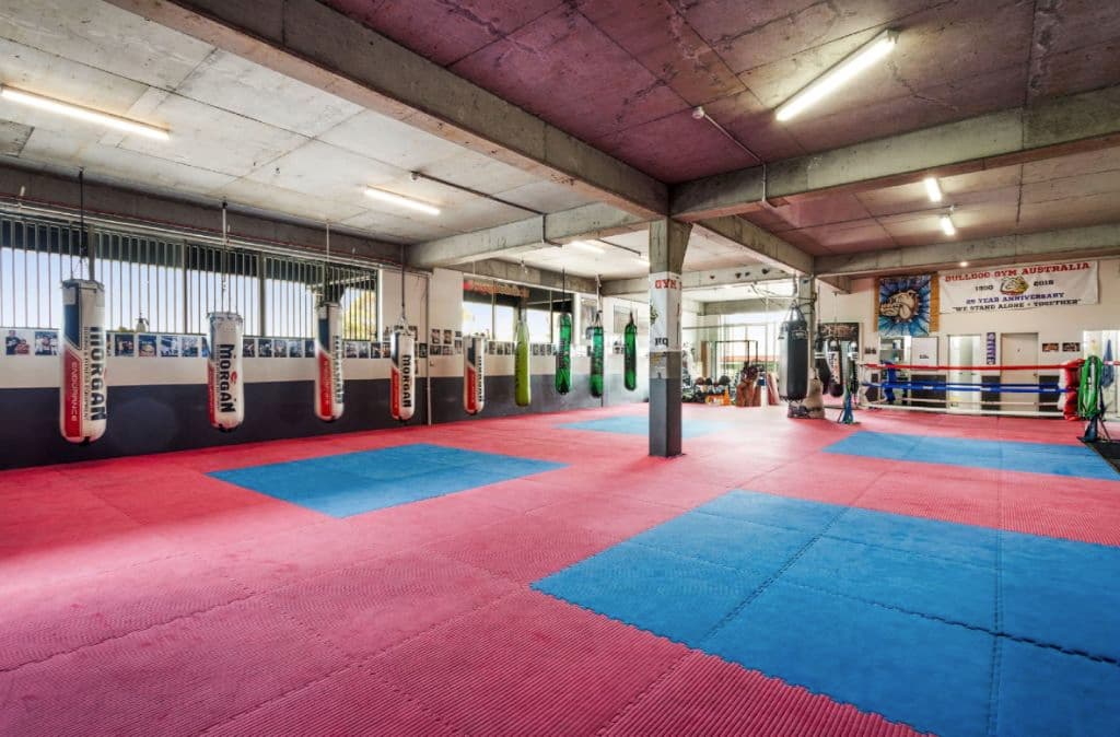 Inside a gym used as a boxing space with red and blue floor mats.