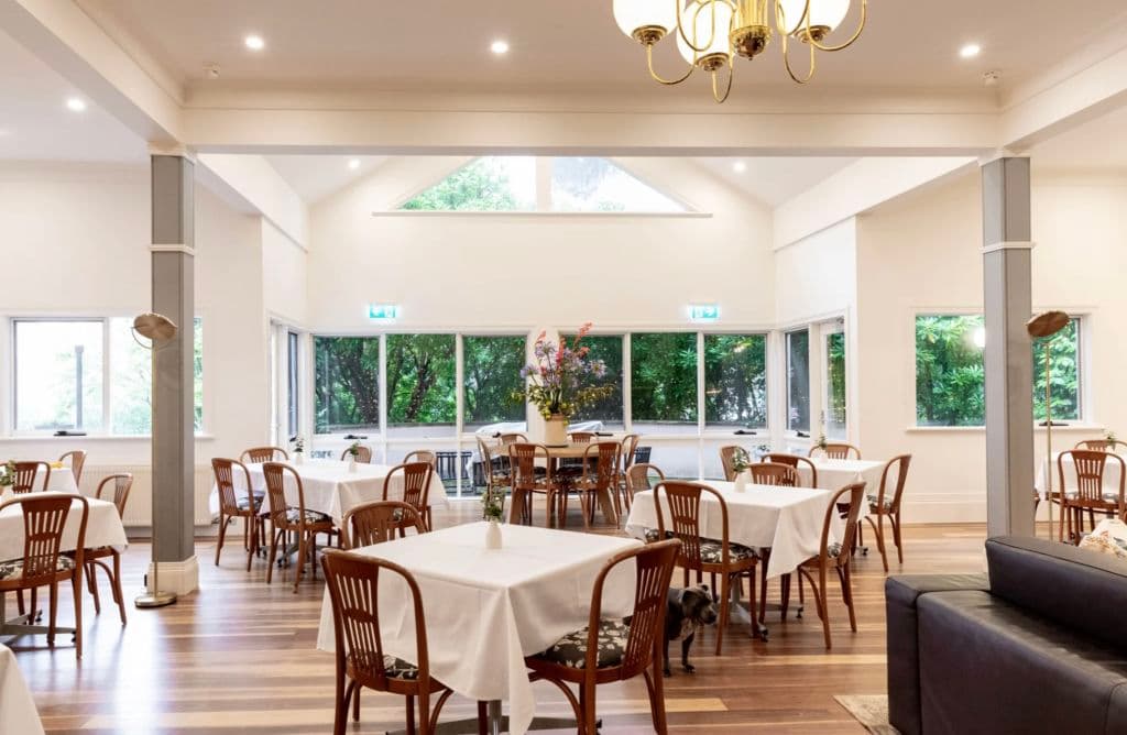A dining space with small tables with white tablecloths.