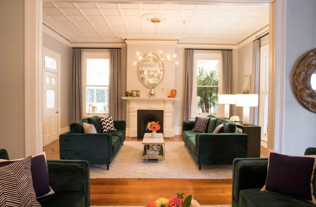 Inside a sitting room with timber floors and furniture around a fire place.
