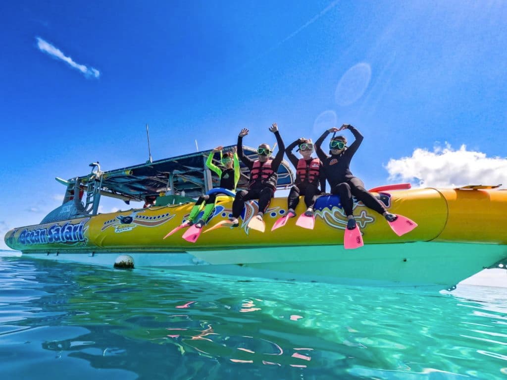 People sit on the edge of a boat with flippers and snorkel gear in the water.