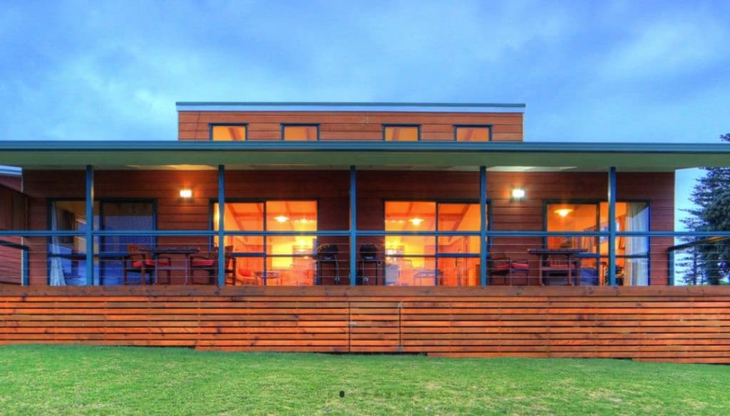 A timber-clad accommodation with large balconies and grass surrounds.