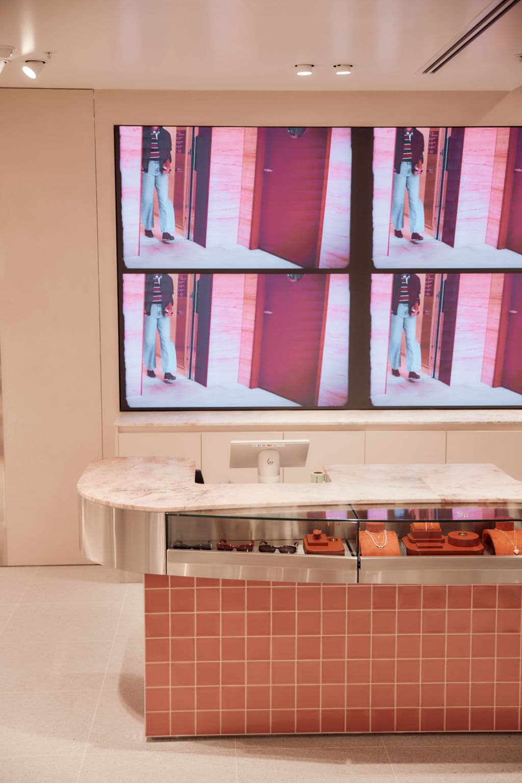 A salmon-coloured tile and marble counter with four TV screens behind