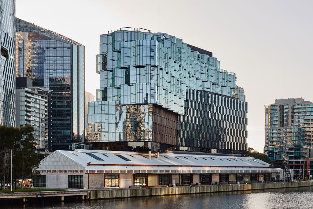 view from river of Seafarers' 1Hotel & Homes with faceted glass building rising above the heritage-listed goods shed