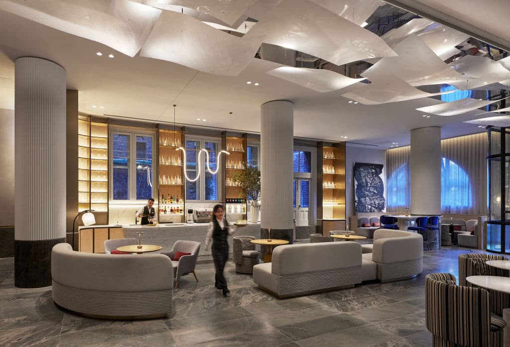 Hotel lobby restaurant with suspended acrylic art installation resembling peeling paper inspired by Melaleuca paperbark tree honouring building's 1901 printing works