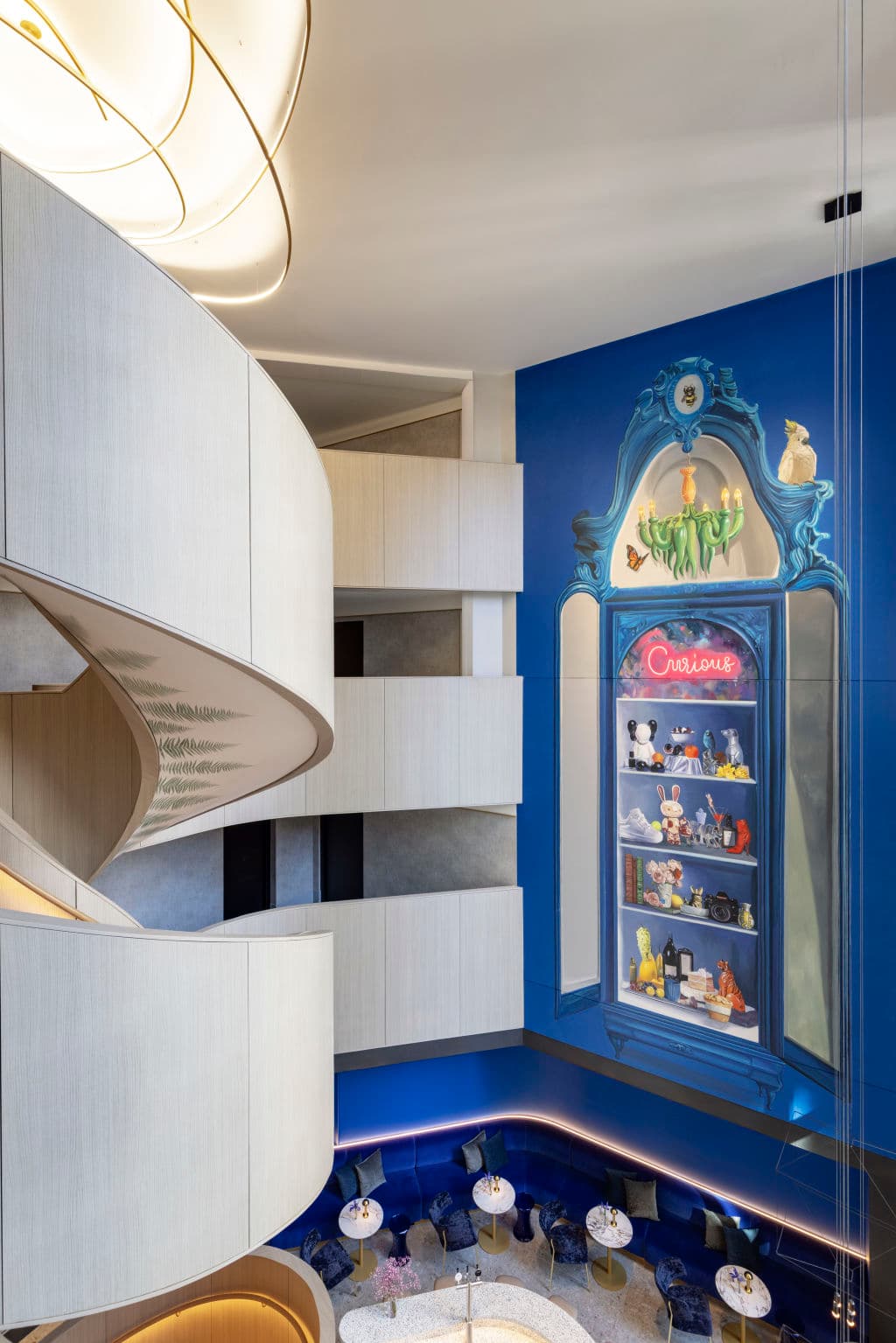 spiral staircase in foreground and painted mural of cabinet filled with curious curios in background