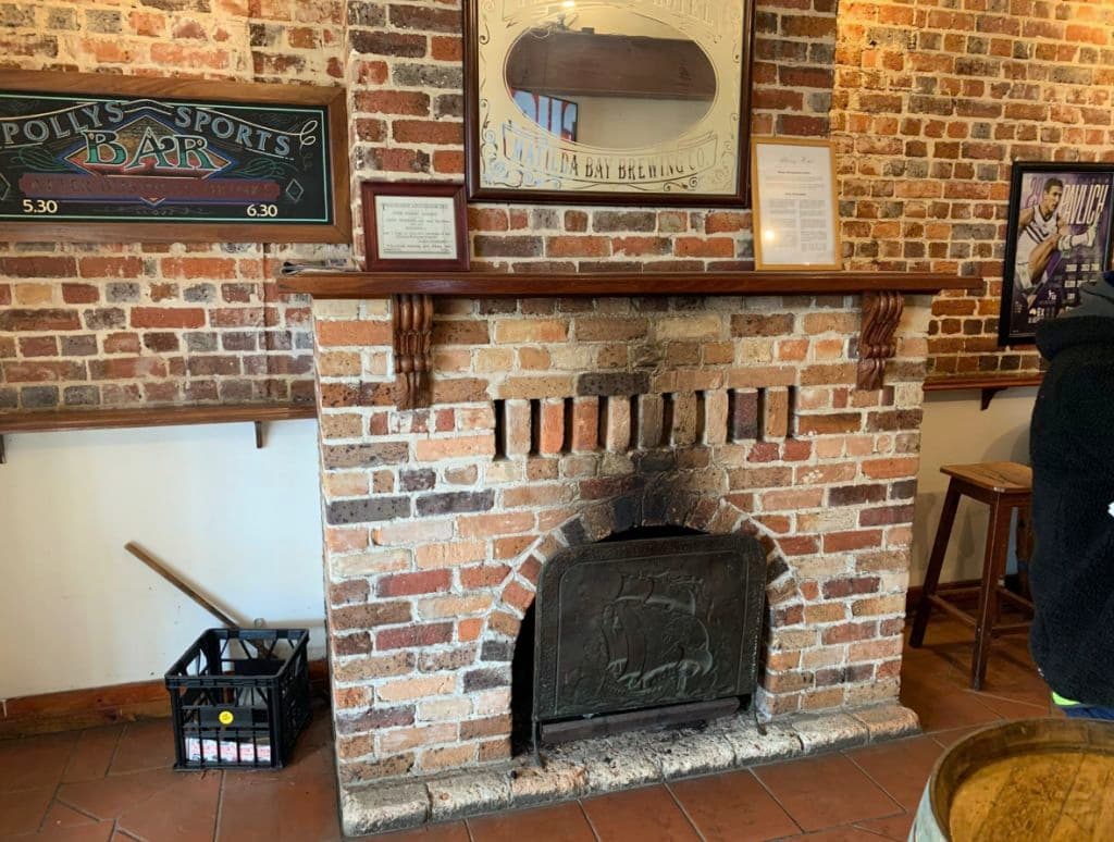 A close up of a brick fireplace with wooden ledge and details.