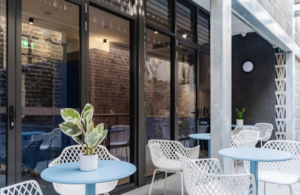 Chairs and a table outside with glass windows.