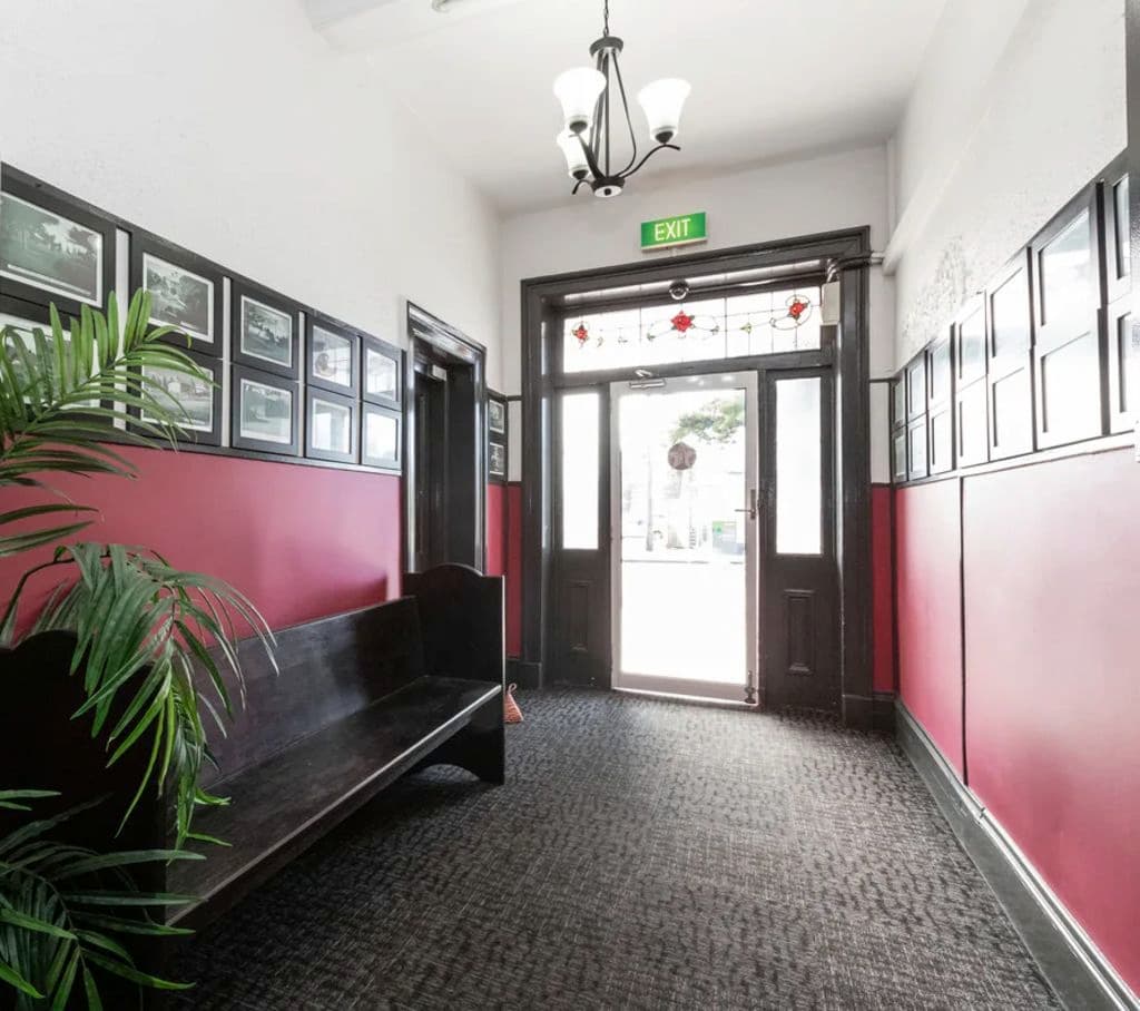 Inside a hallway with a front door and walls lined with photo frames.