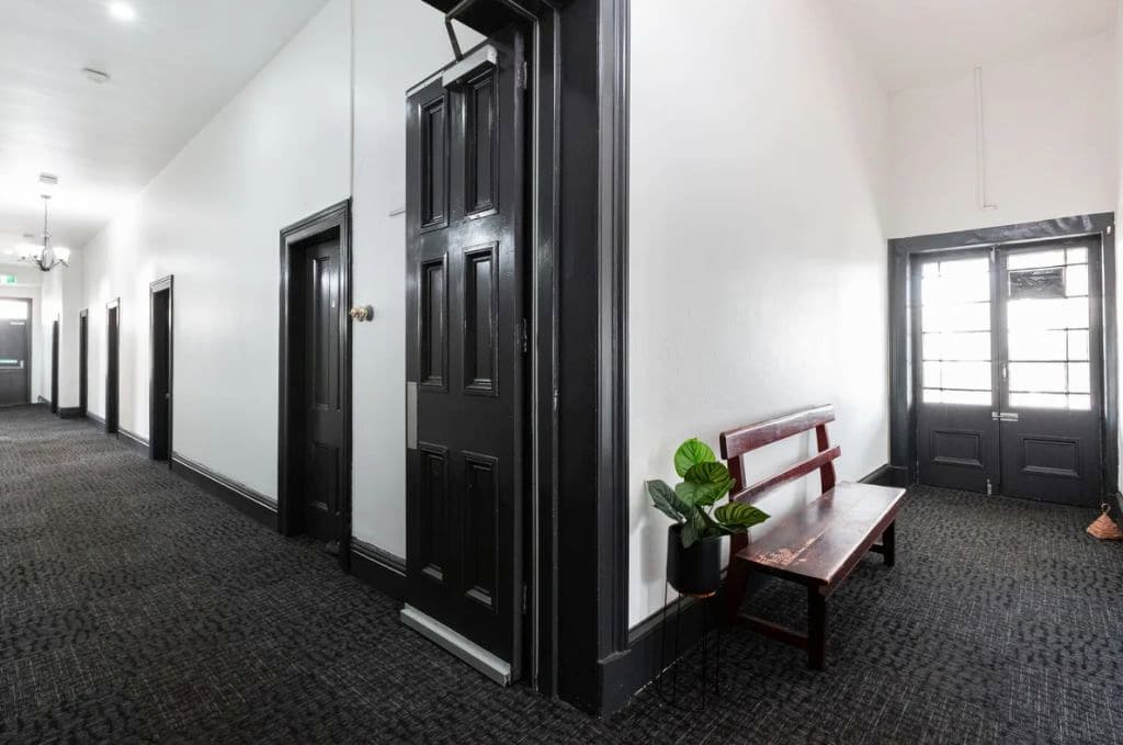 The hallway is lined with seating and reveals black and white painted walls and doors.