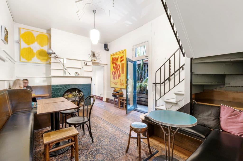 A back room with a staircase and fireplace and casual seating with a floor rug.