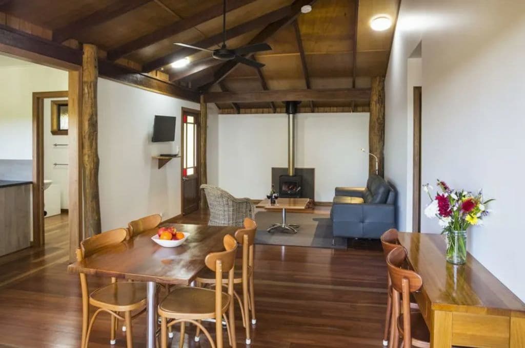 A fireplace at the end of a living room with timber floors and a wooden table and chairs