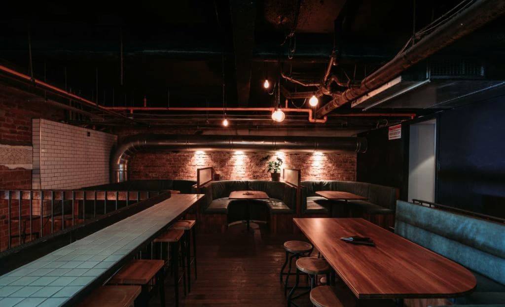 A darkly-lit bar area upstairs has tables and chairs set up.