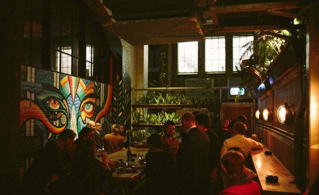 The dark bar shows people drinking in a greenish space with a mural.