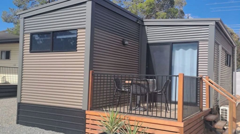 One of the tiny homes shows a balcony with modern seating and a table.