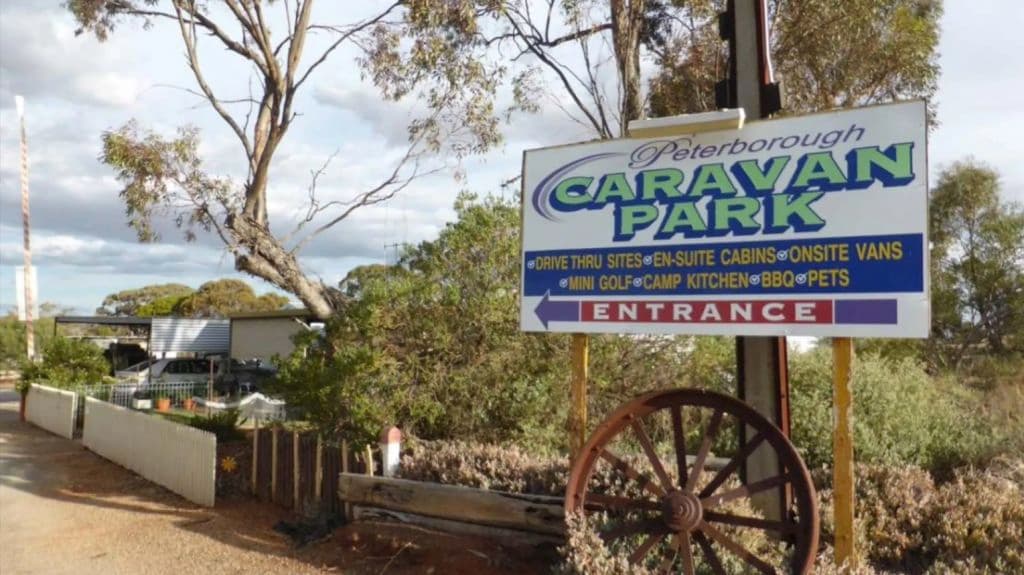 The front signage of the caravan park combines a metal wheel.