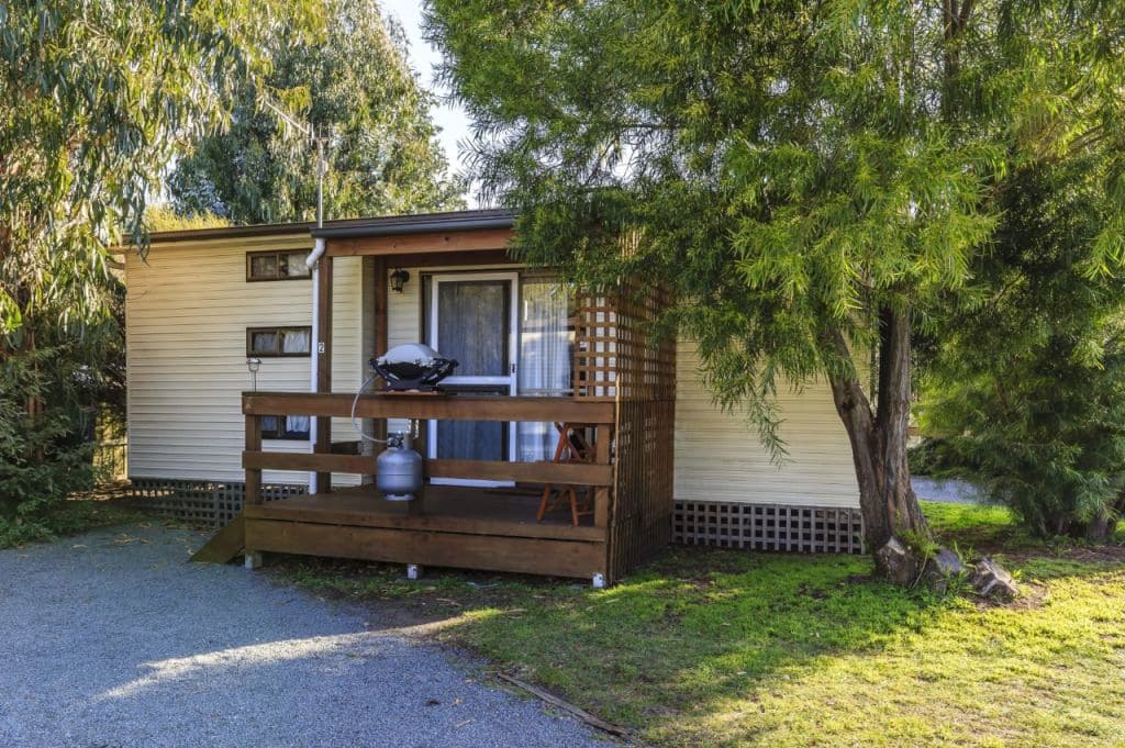 One of the cabins is seen from the front with trees beside it.