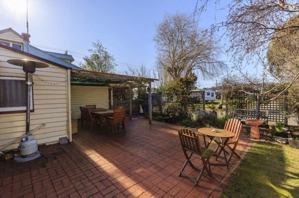 A brick paved courtyard out the back of the weatherboard home.