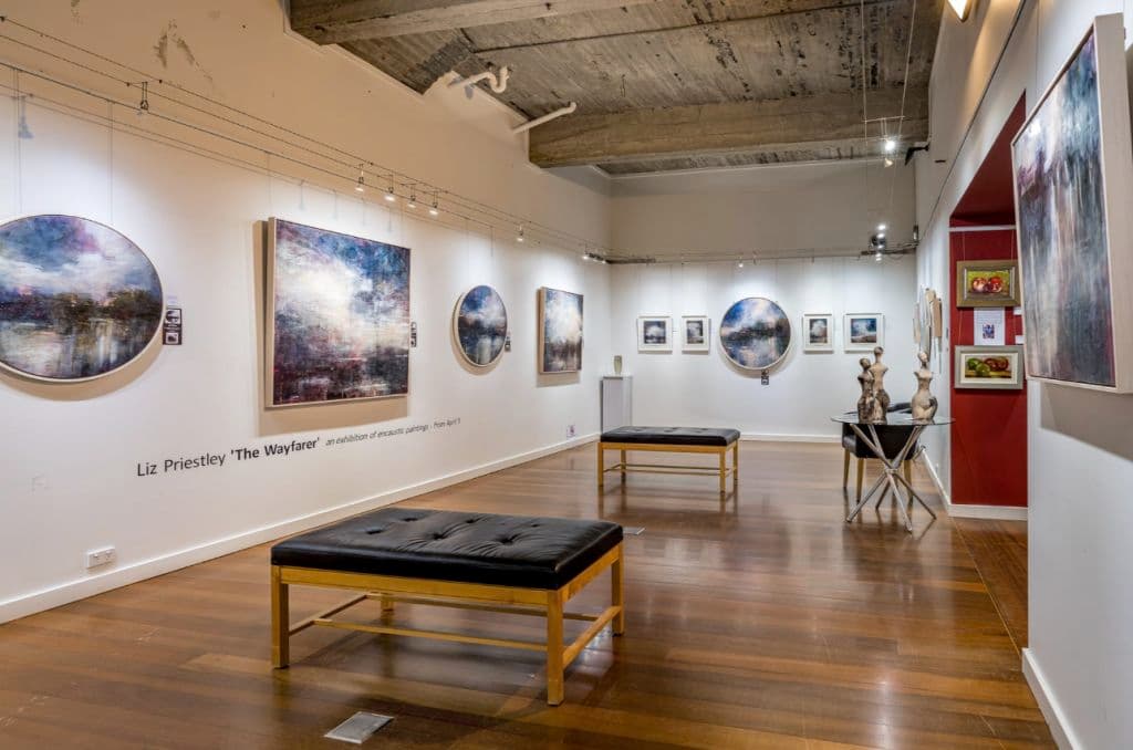 Chairs are positioned through another gallery space with art on walls.