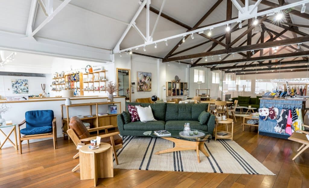 A close up of a couch and some chairs and books in the showroom space.