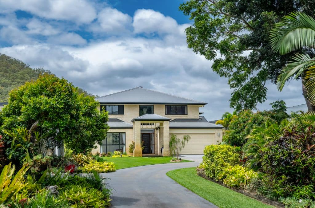 A cream coloured double storey home amid manicured gardens.