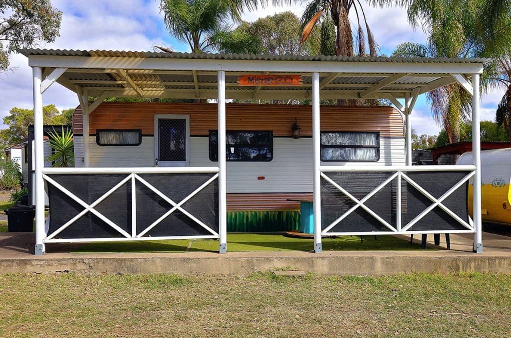 A white and brown caravan with decking in a stable-style to match a horse theme,