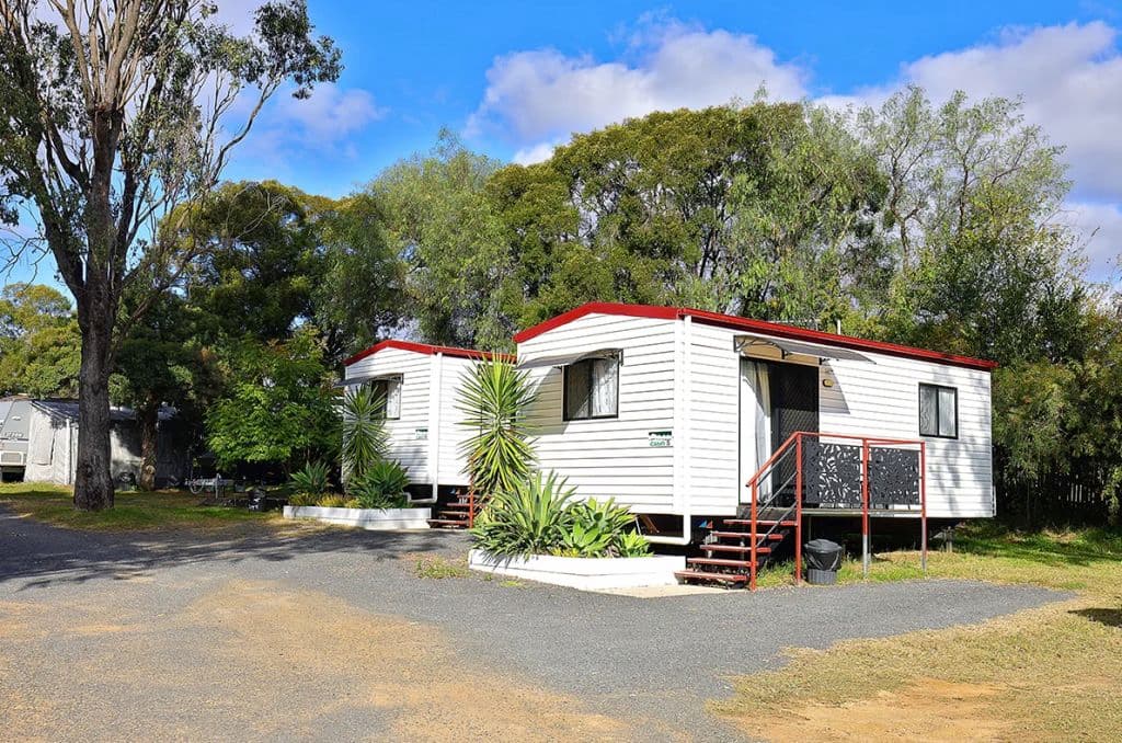 Ensuite cabins are white and red, surrounded by trees.