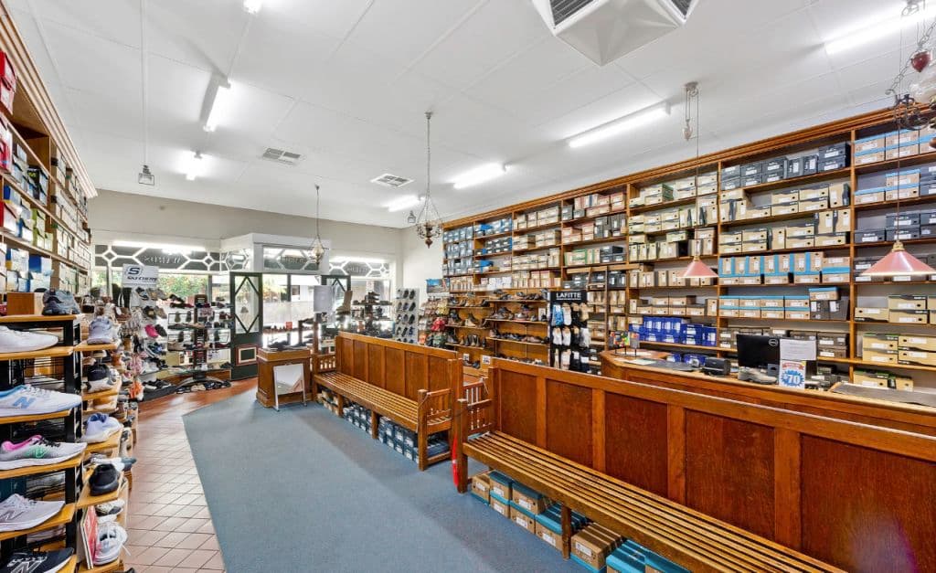Inside the shoe store with shoes lined on walls and timber shelves.