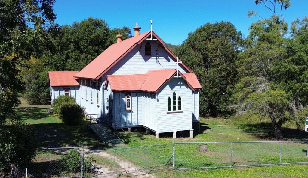 A cute church with a salmon-coloured roof and white timber exterior.