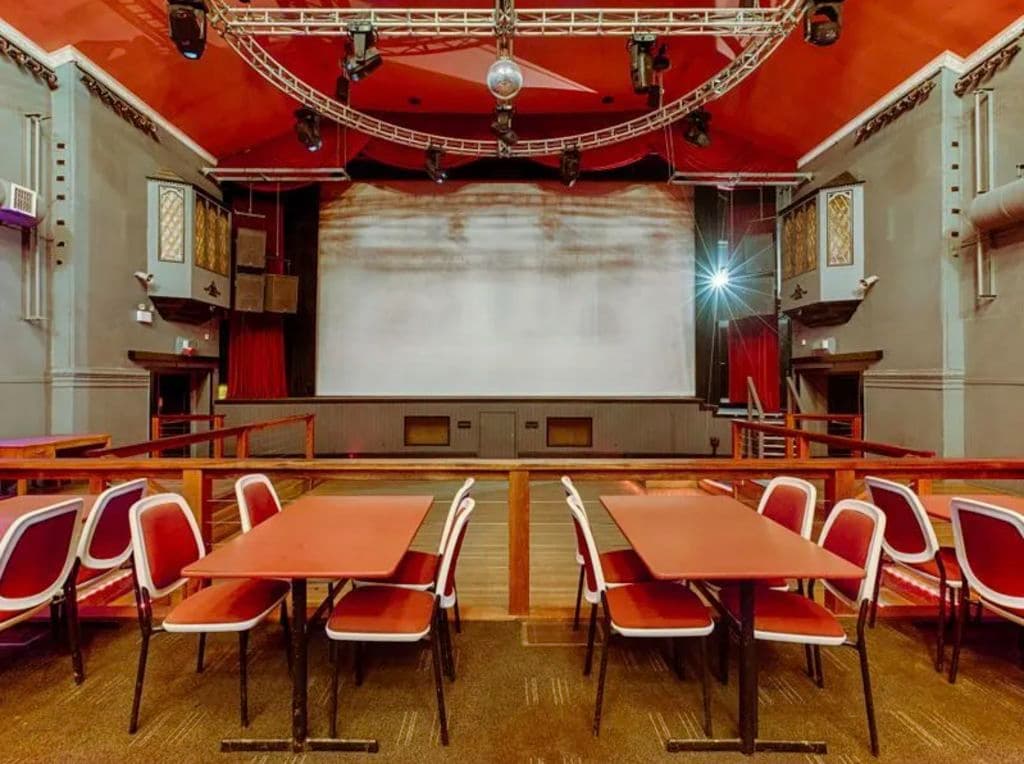 The inside of a theatre with tables and chairs.