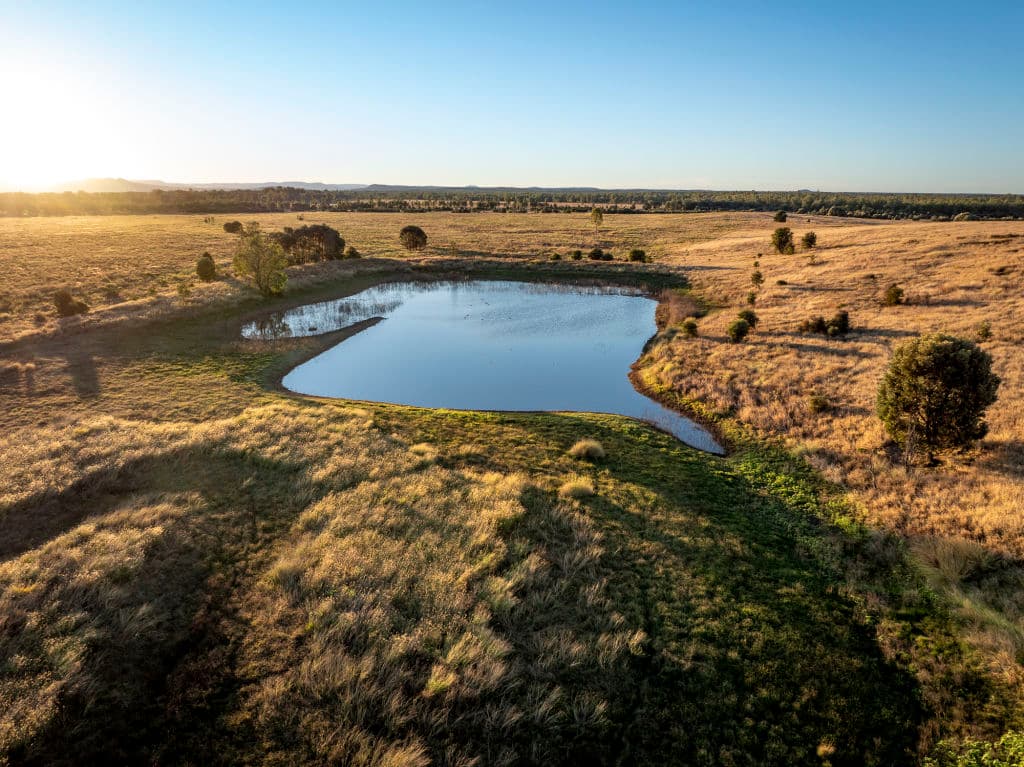 A smallish dam glistens surrounded by farming land.