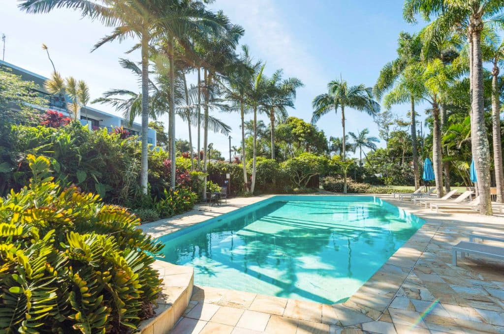 A pool with palm trees around it.