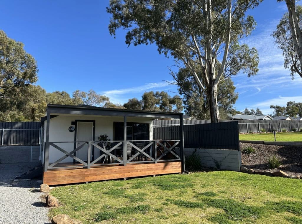 A cabin with decking next to a tree.