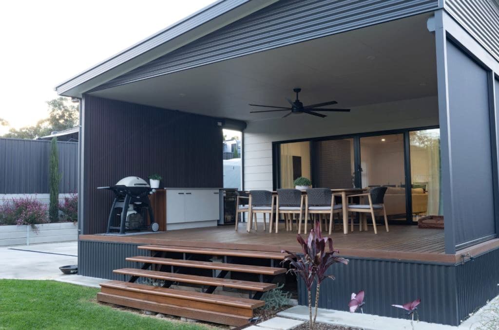 A modern back deck with a BBQ and seating and a fan.