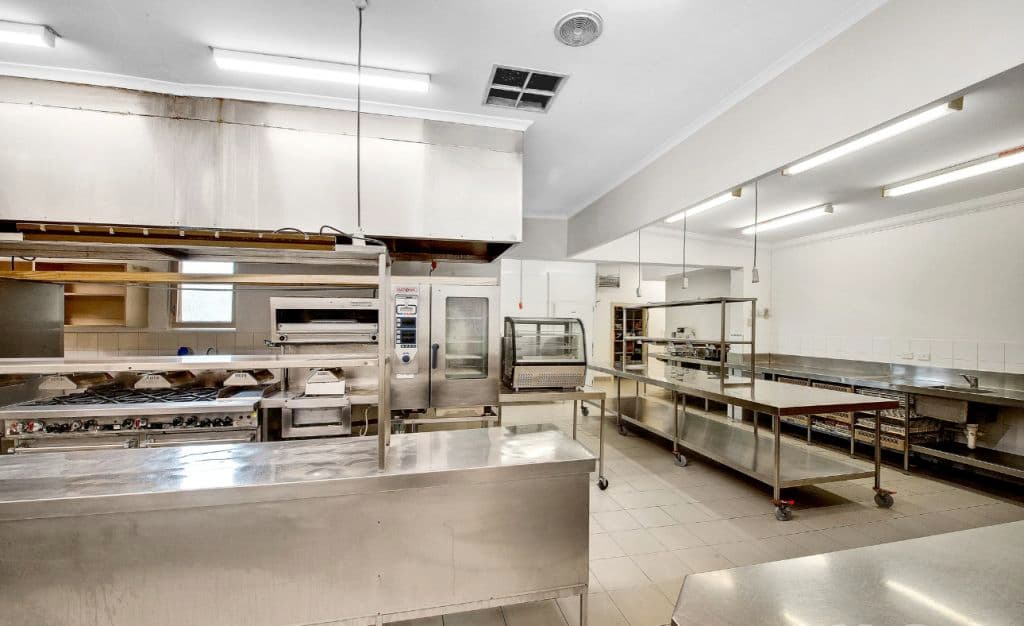 A commercial kitchen with metallic benches and vast space.
