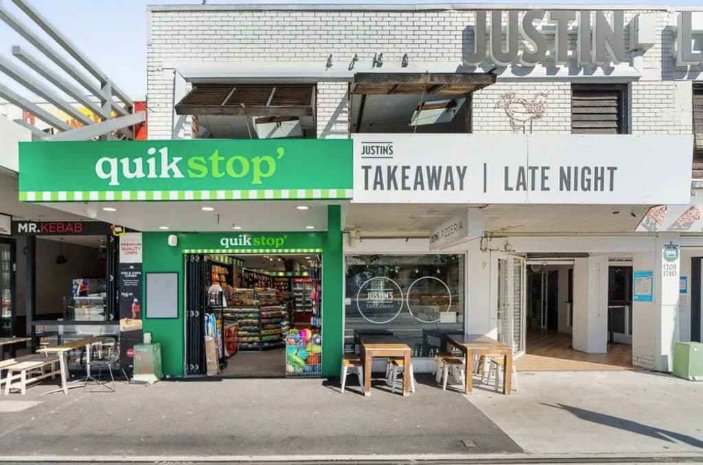 A bright green space for Quikstop part of to the white painted brick Justin Lane building.